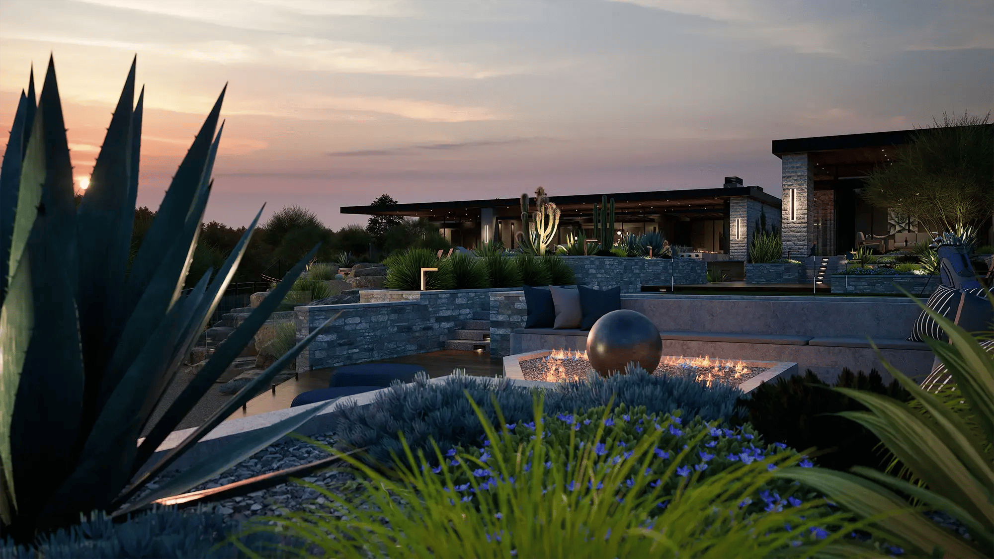 Custom tiered outdoor living design with fire feature, desert plantings, and ambient sunset lighting
